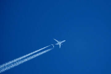 Airplane in the blue sky with contrail. Flight Path Over Blue Sky, travel concept.