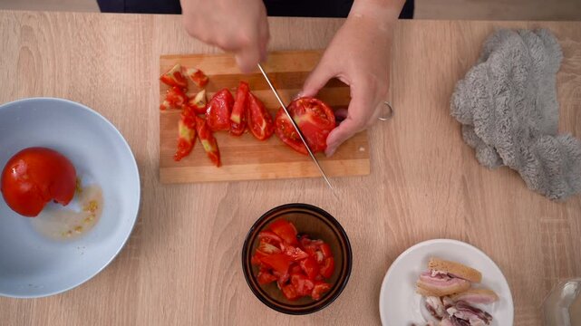 Cutting tomatoes for making eggs with salo and vegetables for breakfast at home
