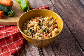 Healthy couscous meal on wooden background with red kitchen towel