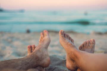 Feet of a couple on the beach at sunset
