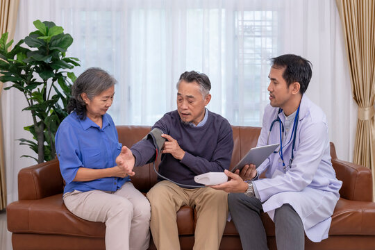 health visitor using tablet computer giving advice a senior woman for checking blood pressure her husband at home,concept for home health services,home care,self health care