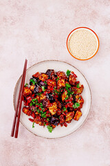 fried eggplant, Chinese style, in sweet and sour sauce, with pepper and sesame seeds. on a white plate,