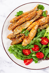 Fried crispy mullet fish, with fresh salad, on a plate with lime, no people,