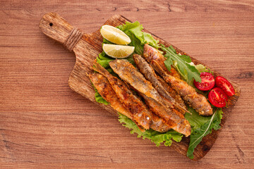 Fried crispy red mullet fish, on a wooden chopping board, with lime, no people,