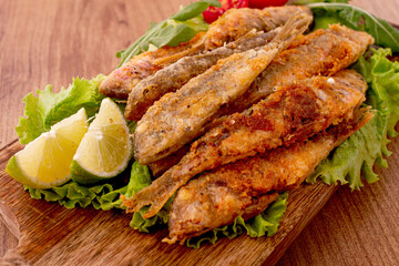 Fried crispy red mullet fish, on a wooden chopping board, with lime, no people,