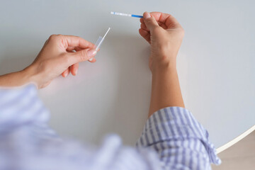 Hands using an at-home rapid antigen test for remote care: self-swab, easy sample, quick result. Ideal for telemedicine, COVID or strep screening, digital health, online doctor pharmacy