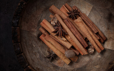 cinnamon sticks, with nutmeg and anise star, in a wooden plate, top view, no people,