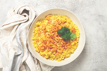 risotto with shrimp, in a bowl, on a textured surface, with a side dish of fresh coriander, homemade, no people,