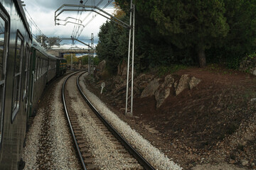 Scenic curve of train on electrified tracks surrounded by pine trees and rocks.