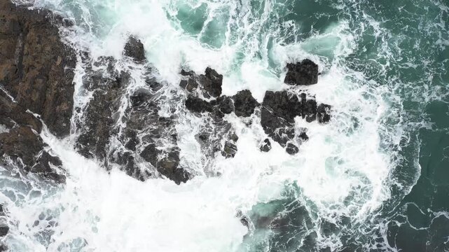 Aerial top view of rocks in the sea - Aerial video of majestic waves splashing on the rocks in Scotland - Travel and nature concepts