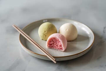 Three pastel mochi ice creams arranged artfully with chopsticks beside plate