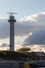 Naklejka premium Coastal lighthouse standing tall against a dramatic sky near the harbor in late afternoon