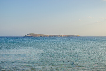 Calm blue sea with distant rocky island under clear summer sky
