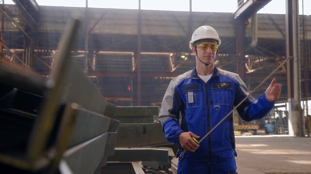 Smiling male worker in factory with safety gear and blue uniform, Technical Control Department.