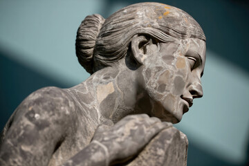 Fototapeta premium Closeup of a weathered stone statue of a woman with her hair in a bun