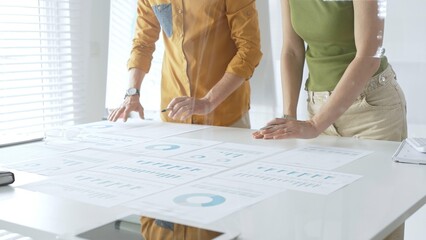 Professional business team members are reviewing financial data, analyzing charts and graphs, during a productive meeting in a modern office. Businesspeople concept