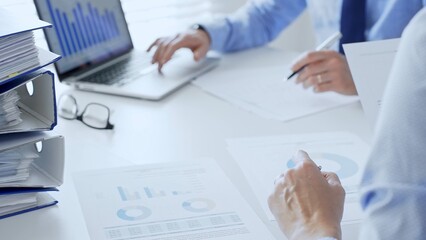 Group of accountants are analyzing financial reports and making notes while sitting at a white table, close up of a stack of blue folders full of paperwork. Audit and taxes in business © rogerphoto