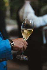 Elegant moment captured as a hand holds a glass of champagne at a sophisticated event. The scene suggests celebration, refinement, and social interaction, emphasizing style and class.