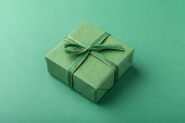 Emerald Gift: A neatly wrapped present, adorned with a delicate ribbon, sits gracefully on a soft emerald surface, symbolizing elegance and anticipation.