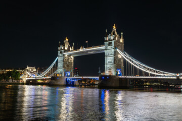 Obraz premium Tower bridge glowing with lights over the river thames at night, a famous london landmark and historic engineering structure