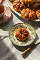 Pumpkin shaped yeast buns with marzipan filling served on vintage plates with tea and natural Autumn decorations on the table.