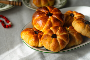 Pumpkin shaped yeast buns with marzipan filling served on vintage plates with natural Autumn decorations on the table.