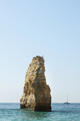 Naklejka premium An iconic stone or rock formation in the sea water next to the beach Praia do Carvalho in Algarve, Portugal. Famous beach has soft golden sand, striking rock formations, and unbelievably clear water.