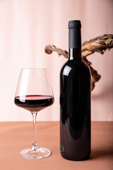 Bottle and a glass of red wine with a composition of old wood. Minimalistic composition with light background for product branding, identity, and packaging