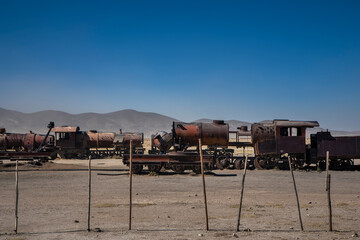 An abandoned locomotive cemetery in Uyuni. Old, rusty, forgotten trains in Bolivia. Sunny day. Blue sky.