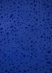 Clean blue glass is covered in a beautiful texture of transparent drops and wet bubbles