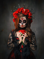 real person close-up portrait body art woman sugar skull make-up beauty face eyes lips, hand holding red rose flower. Black Halloween holiday make up. Sexy Girl Calavera day of the dead santa muerte