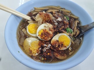 Egg Noodle Bowl Delight: A top-down shot unveils a vibrant bowl of savory egg noodles, beautifully adorned with halved, perfectly cooked eggs and complemented by chopsticks.