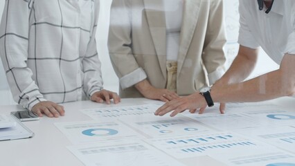 Business team analyzing financial charts and graphs, pointing at statistics and discussing data, working together on business project in modern office. Business people concept