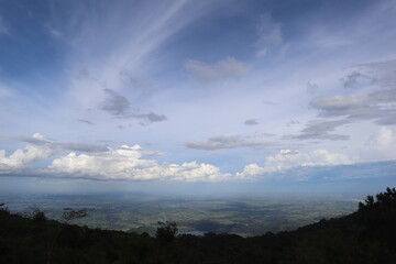 Scenic Vista: An expansive panorama of rolling hills and valleys unfolds beneath a captivating sky dotted with fluffy clouds.