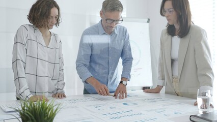 Professional colleagues reviewing financial reports, collaborating on strategic planning in contemporary workspace with collaborative atmosphere