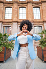 Young manager showing heart sign with hands in front of office building