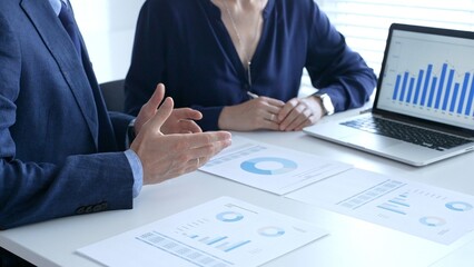 Businesspeople reviewing financial documents, collaborating over laptop screen, analyzing market charts for strategic corporate planning. Business people and finance concept