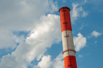Red and White Factory Chimney Against Blue Sky with Clouds