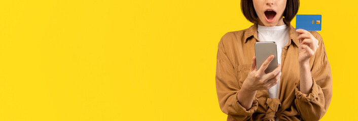 Bonus and cashback concept. Surprised young lady showing debit credit card and using her...