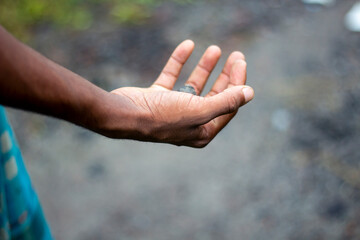 A hand holding a small stone in an open palm