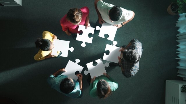 Top view of business people separated jigsaw together at meeting. Aerial view of diverse team put piece of jigsaw puzzle together out and standing while wearing casual cloth at conference. Symposium.