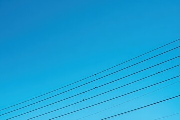 Obraz premium Parallel Power Lines Against a Clear Blue Sky