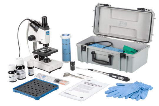 A laboratory microscope with various tools and supplies arranged on a black background. Includes gloves, chemicals, and a storage case.