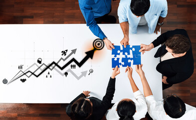 A diverse team engages in a collaborative effort, assembling puzzle pieces symbolizing strategy and growth, set against a backdrop of a positive business graph. Trope
