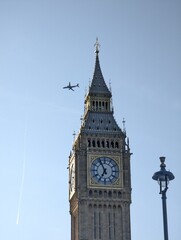 Iconic view of Big Ben with an airplane flying overhead, capturing the blend of historical architecture and modern travel.