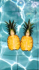 Two halves of pineapples floating in a turquoise pool