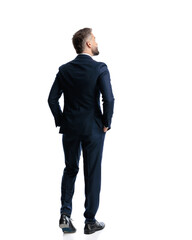 behind view of elegant mature man walking with hands in pockets