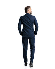 sexy mature businessman in navy blue suit walking with hands in pockets