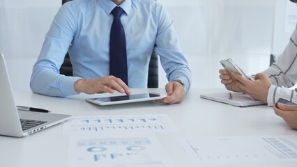 Business team working together, analyzing financial charts and data on digital tablet and smartphones, during a productive meeting in a modern office