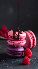 Stacked pink and purple macarons drizzling chocolate sauce
